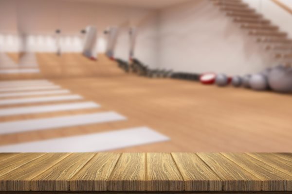 3D render of a wooden table looking out to a defocussed gym interior